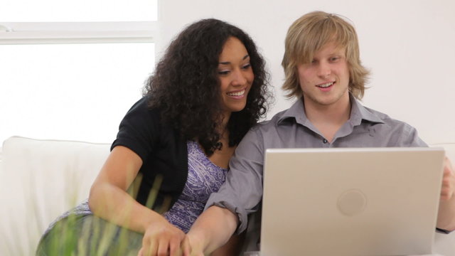 Couple sitting on couch with laptop computer