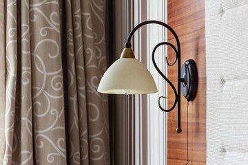 Close up of a lamp in a hotel room, curtains background