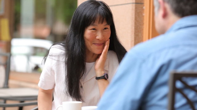 Mature Asian couple having coffee together at an outdoor cafe