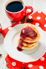 
delicious breakfast, pancakes or fritters called syrnyky from cottage cheese with strawberry or cherry jam , cinnamon and coffee on wooden background