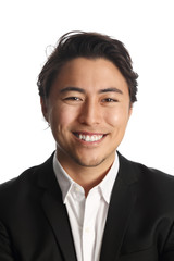 A young and professional businessman standing in front of a white background smiling looking at camera.