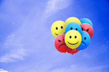Bright balloons flying in the blue sky with a smiley
