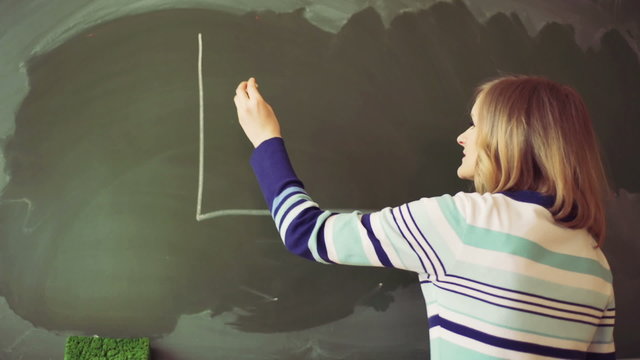 Teacher drawing graph on the blackboard and standing back
