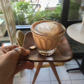 Woman Hand Holding Wooden Tray Of Glass Of Coffee In Coffee Shop