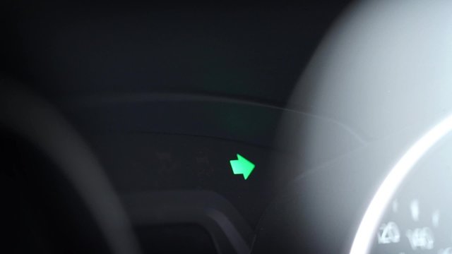 Turn signal light blinking on black car.