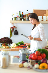 Young woman using a tablet computer to cook in her kitchen
