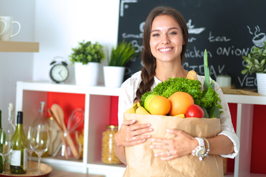 Young woman holding grocery shopping bag with vegetables 