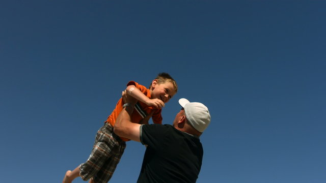 Father throwing son in air, slow motion
