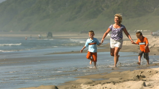 Mom & kids run on beach, slow motion