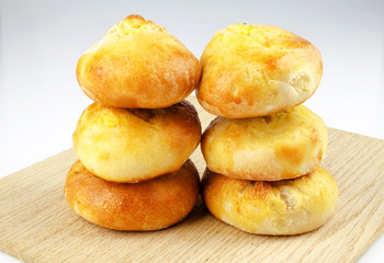 Several freshly baked buns on an oak board