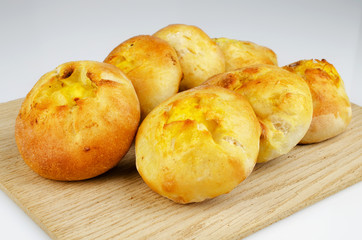 Several freshly baked buns on an oak board