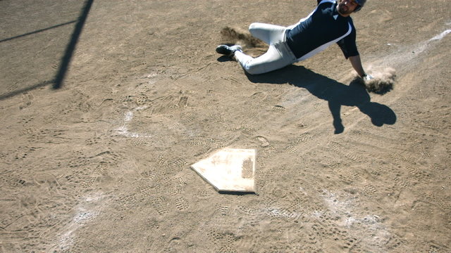 Baseball player slides into home base, slow motion