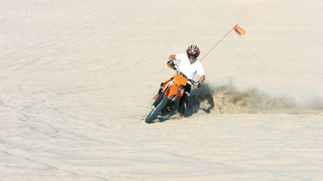 Man riding a motorcycle in sand, slow motion