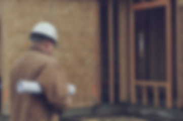 Fototapeta na wymiar Blurred Construction Worker Inspecting Home Construction Site wi