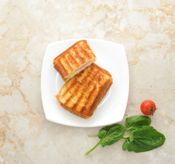 hot sandwiches on a plate with spinach leaves and cherry tomato.