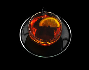 Cup of black tea and lemon on a black background.