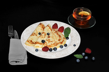 pancakes on a plate with raspberries and blueberries and a mint