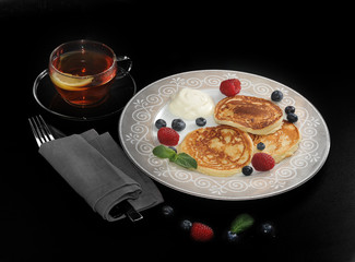 pancakes with sour cream on the plate with raspberries and blueb