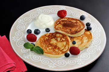 pancakes with sour cream on the plate with raspberries and blueb