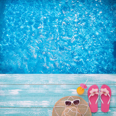 Blue sea. Fashion accessories summer flip flops, hat, sunglasses on bright turquoise board near the pool