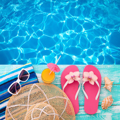 Summer Holidays in Beach Seashore. Fashion accessories summer flip flops, hat, sunglasses on bright turquoise board near the pool