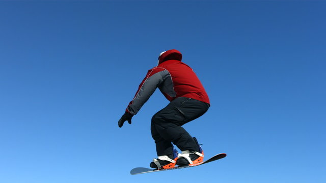 Snowboarder spins in air, slow motion