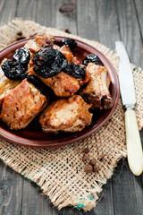 Baked or fried meat , pork ribs with prunes , spices and pepper on a dark wooden background