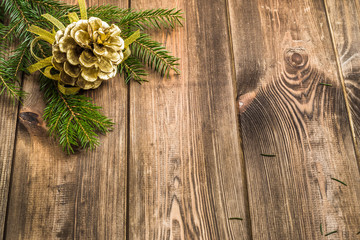 Wooden background with christmas decoration, golden pine cones hanging on branch of christmas tree