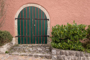 Alte Tür aus Holz in grün und rot mit Beschlägen aus Metall