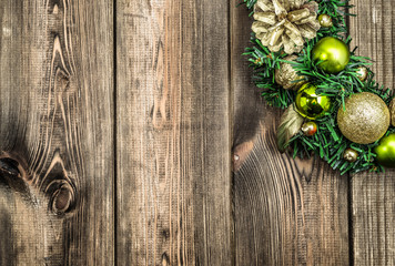 Christmas wreath on wooden door, decoration with ornaments on fir branches on rustic wood in brown