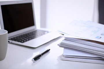 .Office workplace with a laptop and financial documents on the light reflecting table