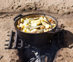 meat with potatoes in a cauldron on fire