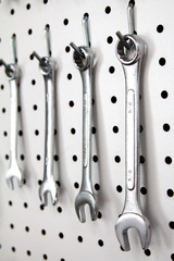 Four combination wrenches hanging on pegboard