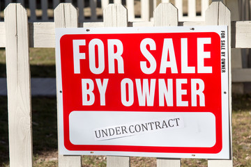 For Sale by Owner sign on picket fence, under contract
