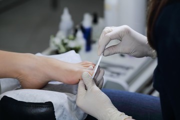 Fototapeta na wymiar Close-up gash nail file toenails in salon. The service is professional pedicure in the spa salon.