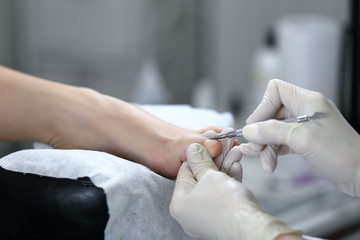 Close up shot of pedicure process, which is made in white gloves