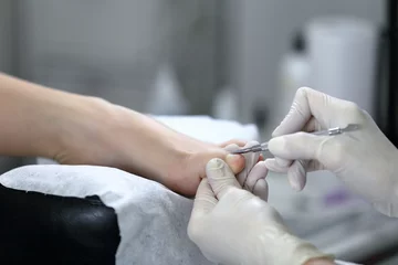Rolgordijnen Close-up shot van pedicure proces, dat is gemaakt in witte handschoenen © belyjmishka