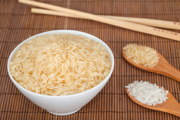 Rice in white bowl on bamboo background. 