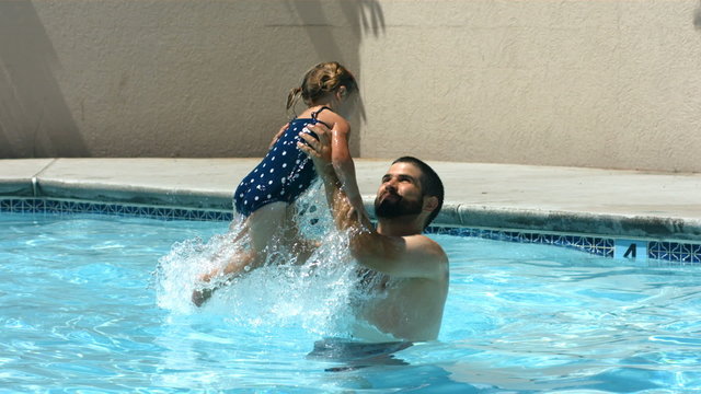 Father and young daughter playing in pool, slow moiton