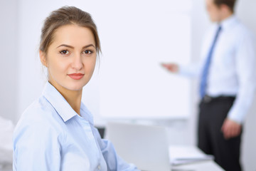 Obraz premium Beautiful business woman on the background of business people during meeting