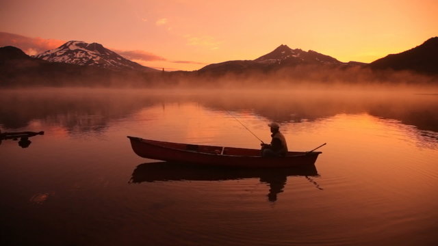 Silhouette of fisherman in canoe at sunrise