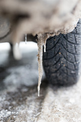 Snowy winter road with tire tracks in snow and tire and icicles