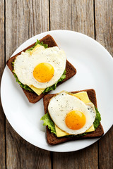 Fried eggs with toasts on plate on grey wooden table