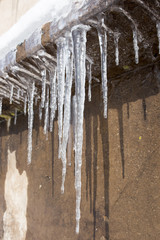 Large icicles hanging on the roof of the house in springtime