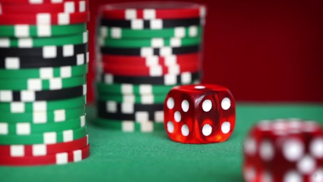 Red dice rolls and casino chips on green table