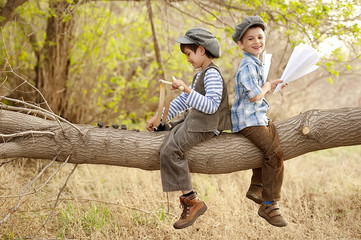 Boys let paper airplanes and shoot with the slingshot, sitting on a tree branch