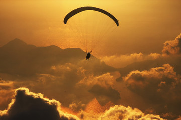 Silhouettes of paragliders over the clouds