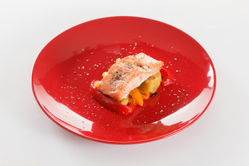 Grilled salmon fillet with vegetables, spices and arugula on a plate