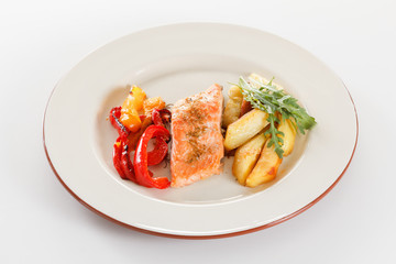 Grilled salmon fillet with vegetables, spices and arugula on a plate