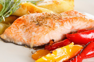 Grilled salmon fillet with vegetables, spices and arugula on a plate